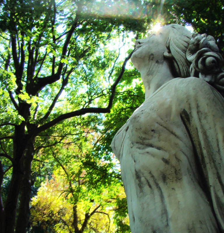 scuplture of woman with green trees