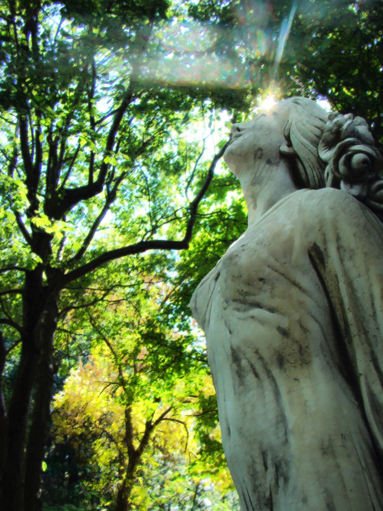 scuplture of woman with green trees